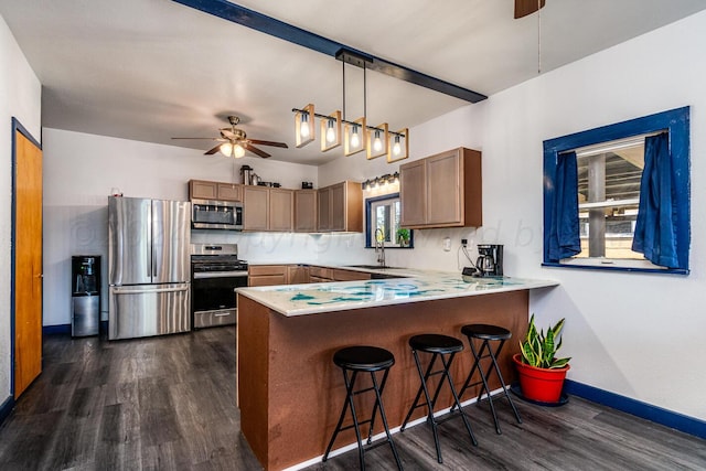 kitchen with dark wood-type flooring, kitchen peninsula, appliances with stainless steel finishes, and decorative light fixtures