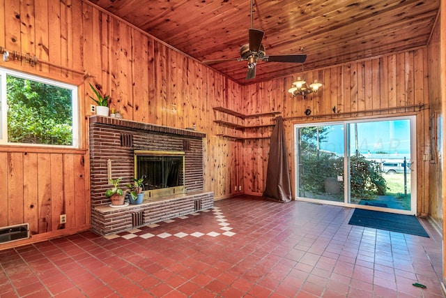 unfurnished living room with a fireplace, a healthy amount of sunlight, wooden walls, and wood ceiling