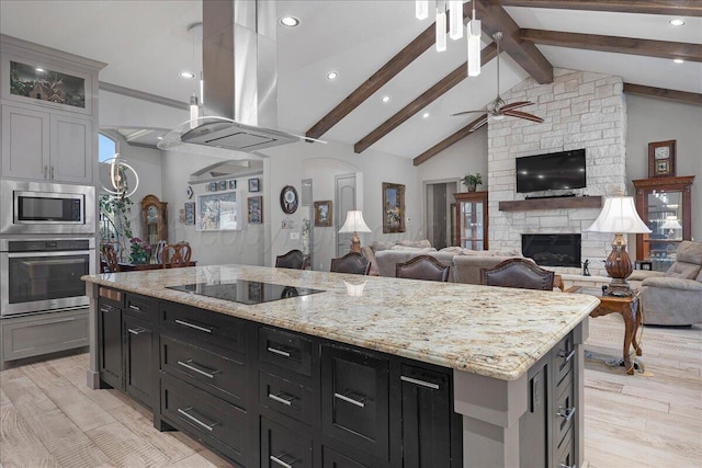 8205 S Liberty Cir, Amarillo, TX 79119 - kitchen with stainless steel appliances, island exhaust hood, open floor plan, a ceiling fan, and a stone fireplace