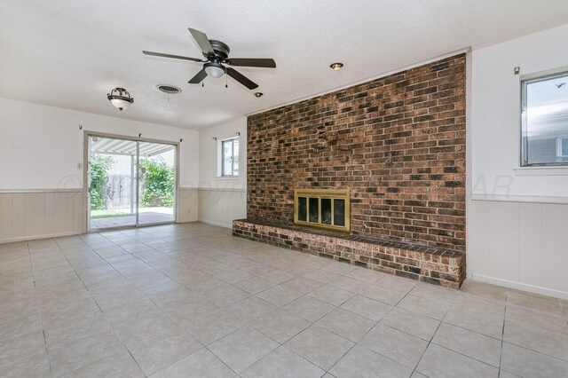 4720 Cherokee Trl, Amarillo, TX 79109 - unfurnished living room with a ceiling fan, a fireplace, wainscoting, light tile patterned floors, and a decorative wall