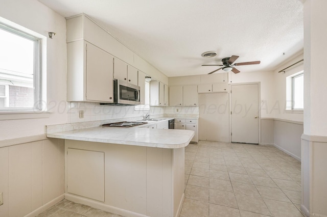4720 Cherokee Trl, Amarillo, TX 79109 - kitchen featuring a peninsula, appliances with stainless steel finishes, light countertops, a ceiling fan, and decorative backsplash