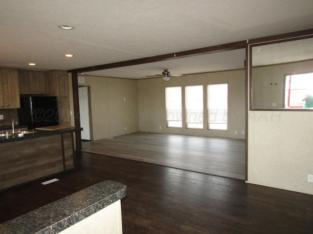 kitchen with dark wood-type flooring, black refrigerator, sink, and ceiling fan