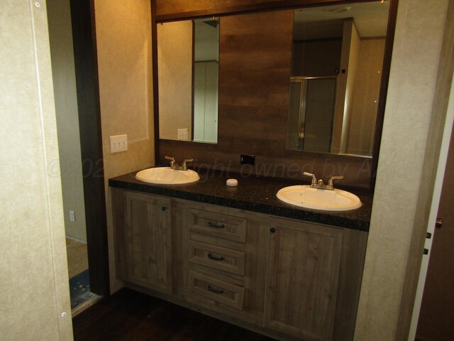 bathroom with vanity, wooden walls, and a shower with door