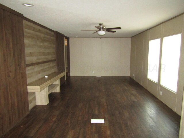 unfurnished room featuring dark hardwood / wood-style flooring, wooden walls, and ceiling fan