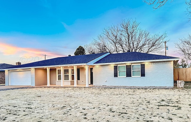 ranch-style house featuring a garage, fence, concrete driveway, and brick siding