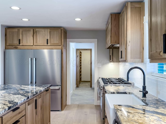 kitchen featuring stone countertops, appliances with stainless steel finishes, tasteful backsplash, and a sink