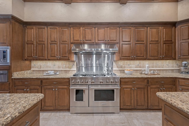 3506 Van Winkle Dr, Amarillo, TX 79121 - kitchen featuring a textured wall, stainless steel appliances, backsplash, light stone countertops, and ventilation hood