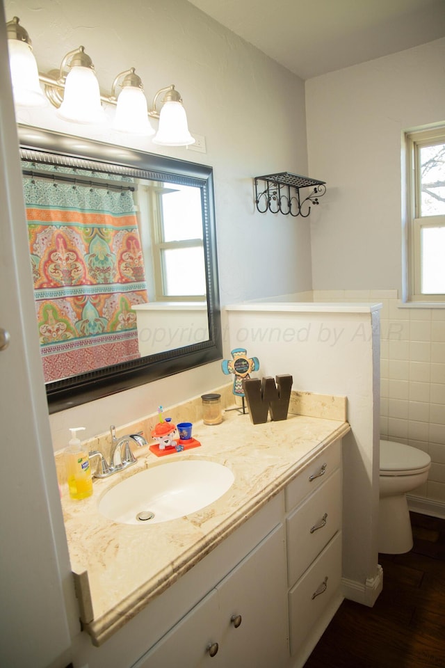 1418 Oak Ave, Panhandle, TX 79068 - full bathroom featuring vanity, tile walls, wood finished floors, a wainscoted wall, and a shower with shower curtain