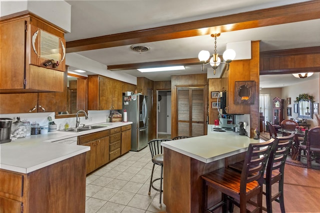 kitchen with stainless steel fridge with ice dispenser, a breakfast bar area, a peninsula, light countertops, and pendant lighting