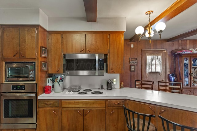 kitchen featuring brown cabinetry, hanging light fixtures, stainless steel appliances, light countertops, and beam ceiling