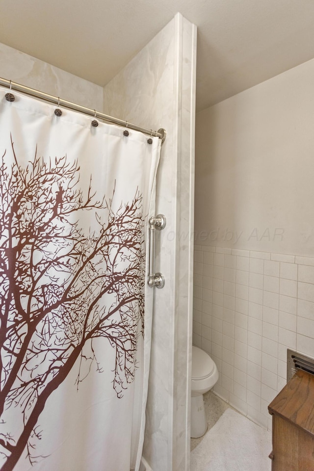 full bath with a wainscoted wall, tile walls, a shower with curtain, toilet, and tile patterned flooring