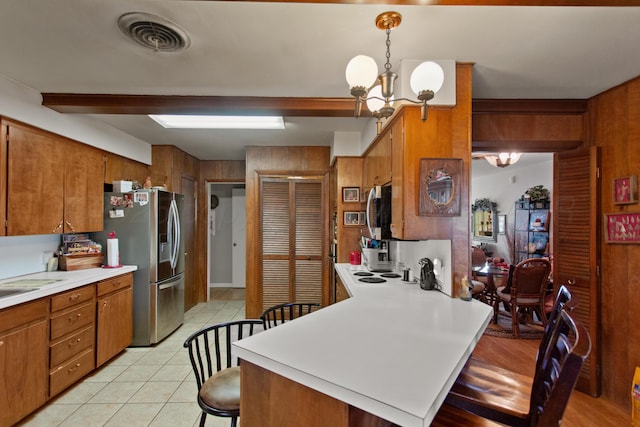 kitchen featuring decorative light fixtures, a kitchen bar, light countertops, visible vents, and stainless steel fridge with ice dispenser