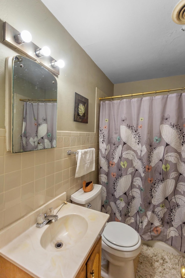 bathroom with toilet, a shower with curtain, vanity, and tile walls