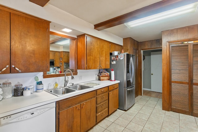 kitchen featuring stainless steel fridge, brown cabinets, white dishwasher, light countertops, and a sink