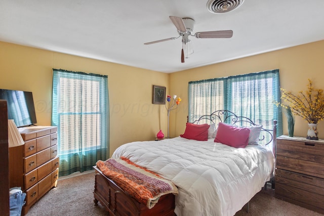 bedroom featuring a ceiling fan, multiple windows, visible vents, and carpet flooring