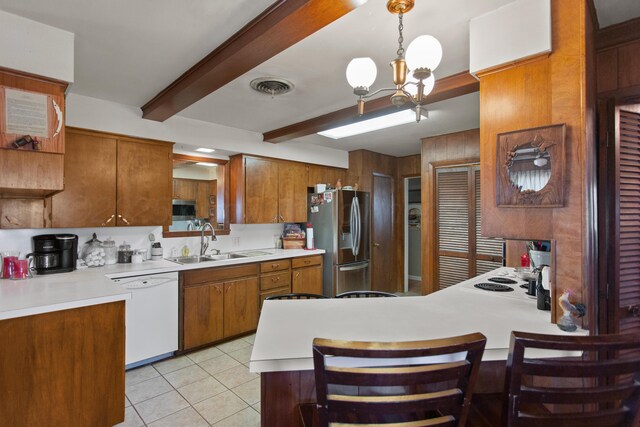 kitchen with white appliances, light countertops, hanging light fixtures, and a sink