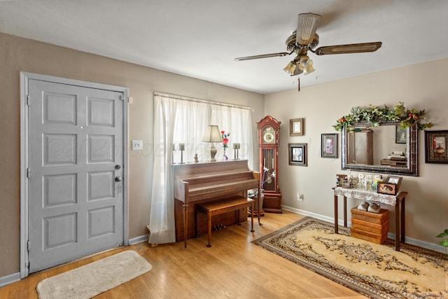 foyer entrance with baseboards, ceiling fan, and light wood-style floors