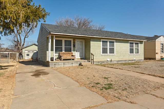 view of front of property with a porch, concrete driveway, roof with shingles, and fence