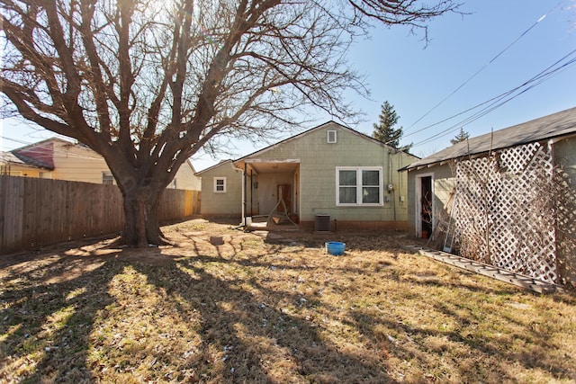 back of house featuring a yard, concrete block siding, fence, and central air condition unit