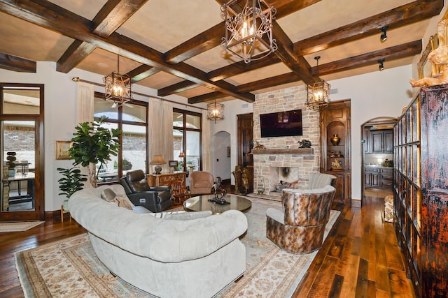 living room featuring beam ceiling, dark hardwood / wood-style floors, coffered ceiling, a notable chandelier, and a large fireplace