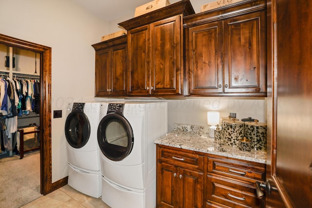 laundry room featuring washer and clothes dryer, cabinets, and light tile patterned flooring