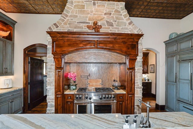 kitchen featuring light stone counters, double oven range, dark wood-type flooring, and backsplash