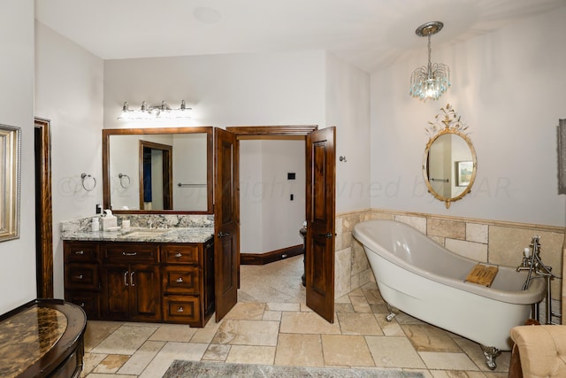 bathroom with tile walls, vanity, a tub, and a chandelier