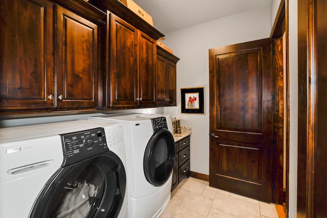 clothes washing area with light tile patterned floors, washing machine and dryer, and cabinets