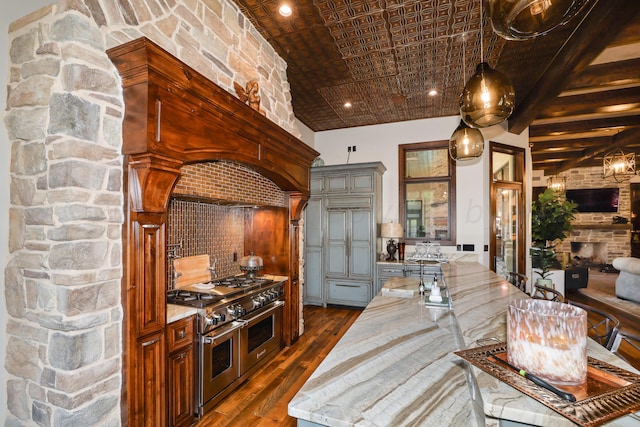 kitchen featuring light stone counters, dark wood-type flooring, range with two ovens, and pendant lighting