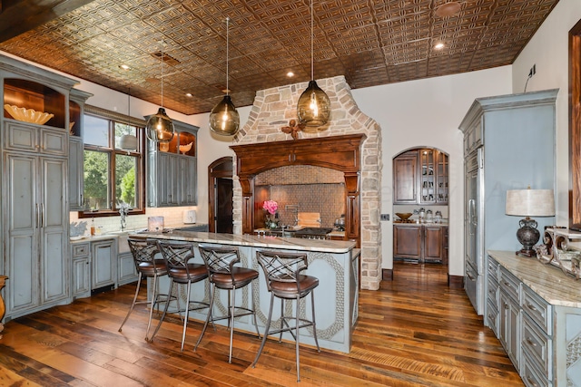 kitchen featuring pendant lighting, gray cabinetry, backsplash, a kitchen breakfast bar, and a center island