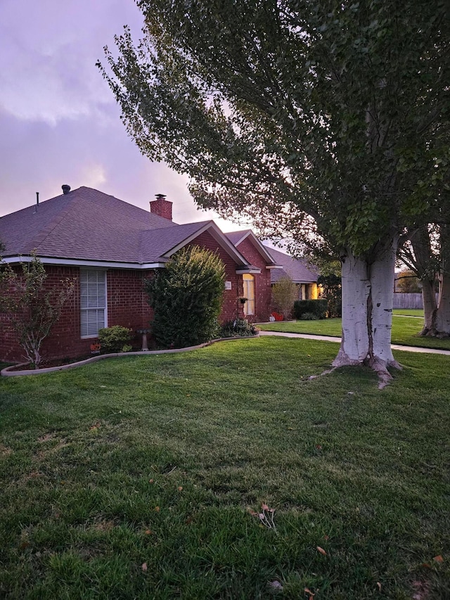 7205 Columbia Ln, Amarillo, TX 79109 - view of front of property featuring a lawn, a chimney, brick siding, and a shingled roof