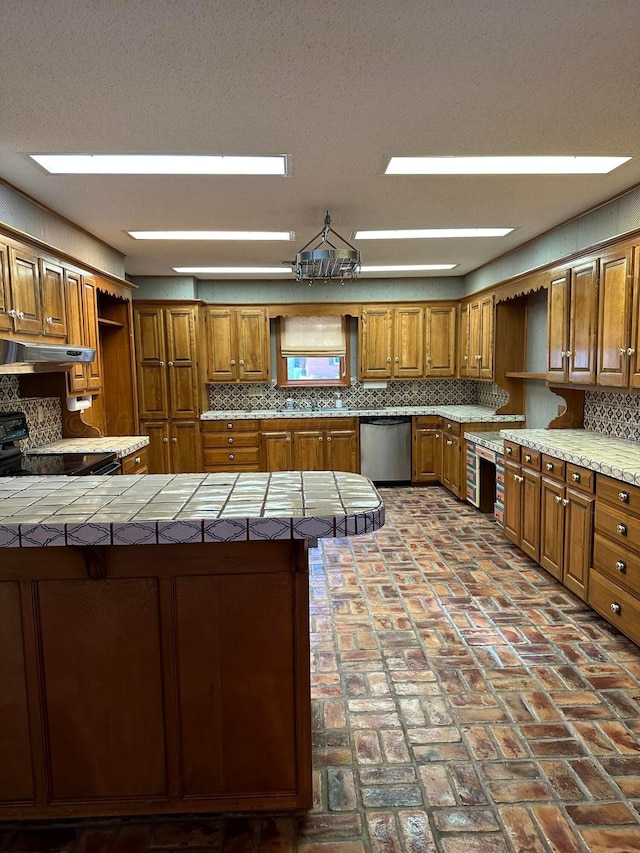 kitchen featuring backsplash, tile counters, and stainless steel dishwasher