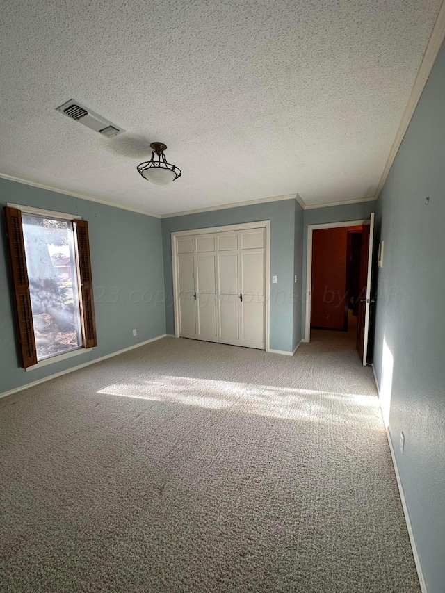 unfurnished bedroom featuring a textured ceiling, carpet flooring, and crown molding