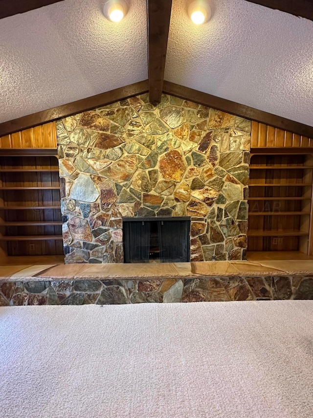 room details with a stone fireplace, wooden walls, a textured ceiling, and beam ceiling