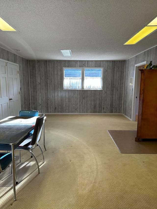 basement featuring a textured ceiling, wood walls, and light carpet