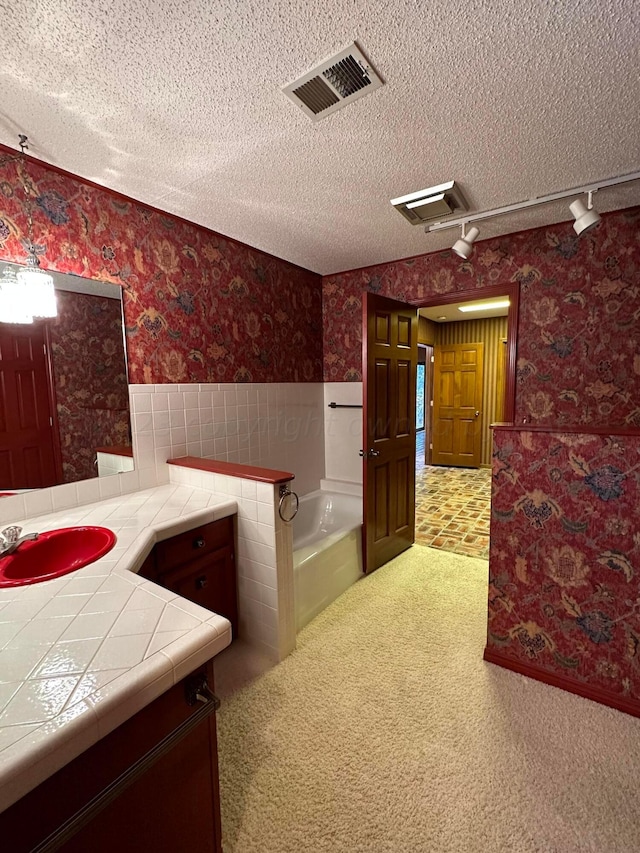 bathroom featuring vanity, a textured ceiling, and a bathtub