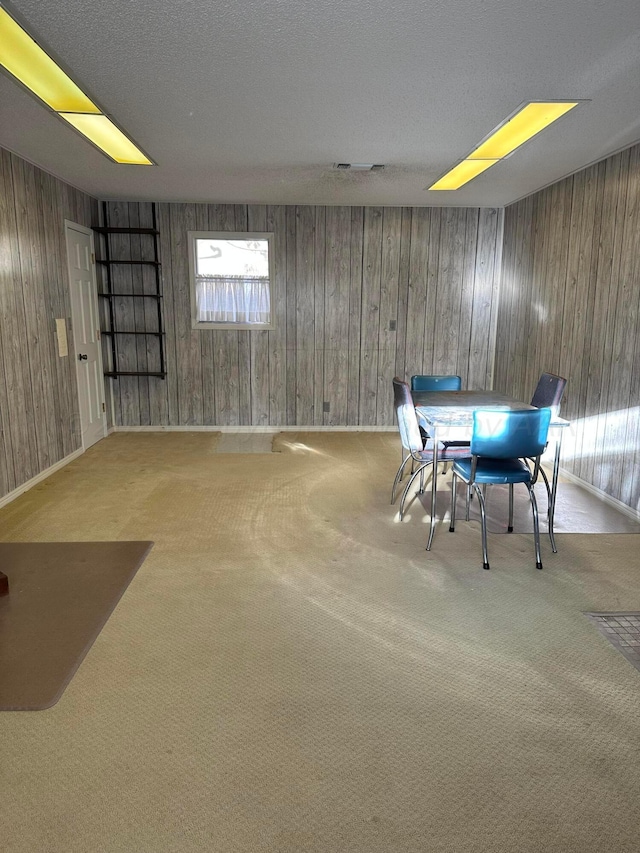 unfurnished dining area featuring wood walls and carpet