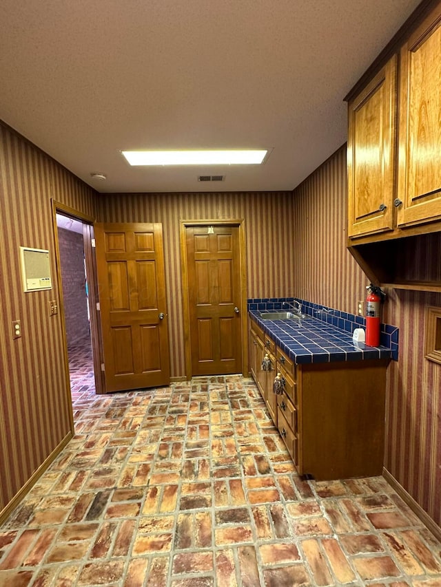 interior space featuring wooden walls, sink, and a textured ceiling