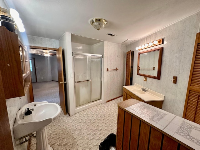 bathroom with double sink, a shower with door, and ceiling fan