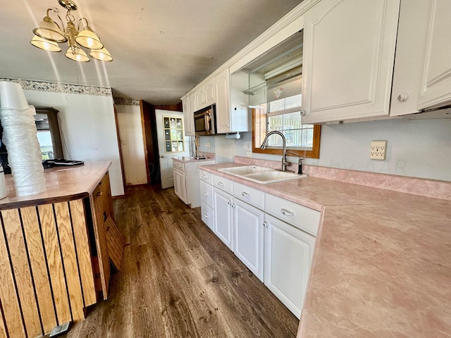 kitchen with pendant lighting, sink, dark hardwood / wood-style floors, and white cabinets