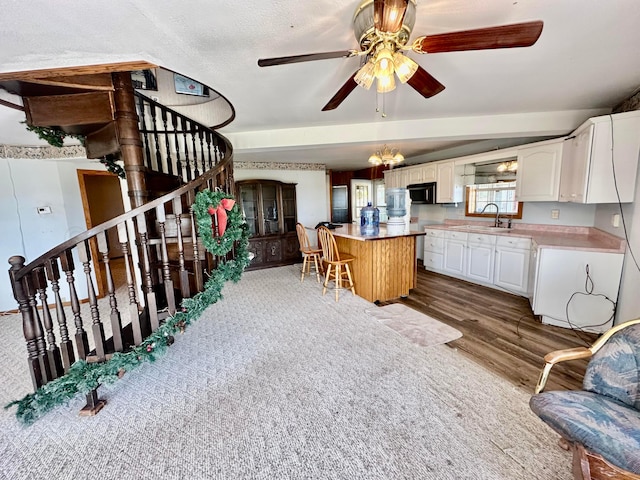 kitchen with a center island, white cabinetry, hardwood / wood-style floors, a kitchen breakfast bar, and ceiling fan with notable chandelier