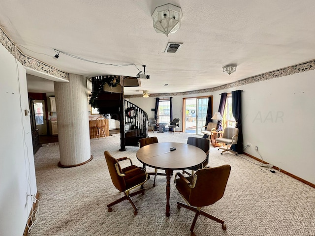 dining area with decorative columns, a textured ceiling, and carpet