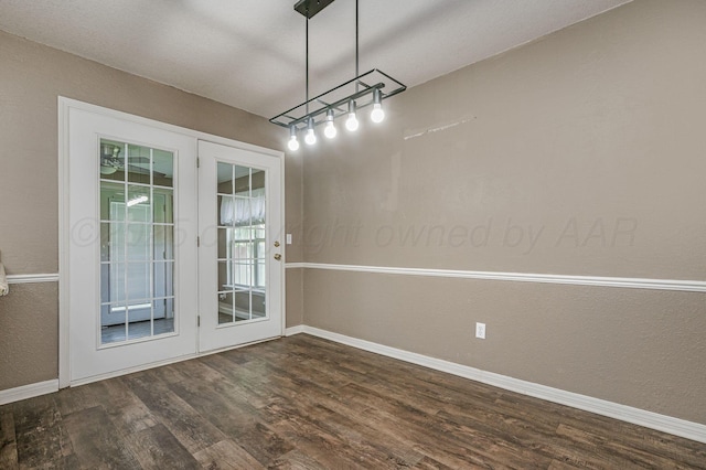unfurnished dining area with baseboards, wood finished floors, and a textured wall