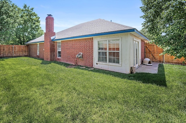 rear view of house featuring a chimney, a shingled roof, and brick siding
