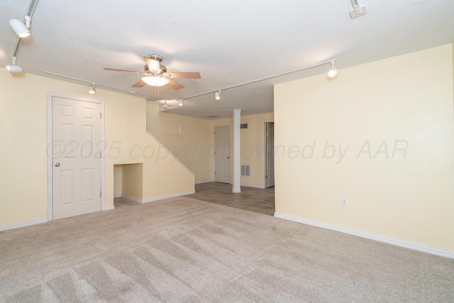 carpeted spare room featuring ceiling fan, track lighting, and a textured ceiling