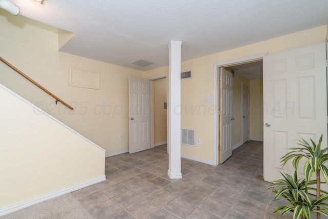 empty room with decorative columns and a textured ceiling