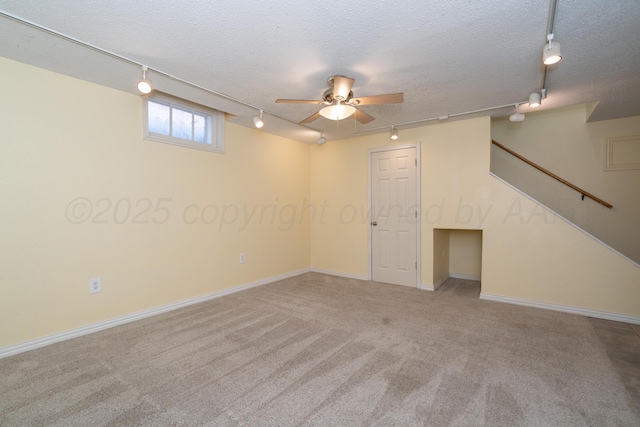 basement featuring track lighting, a textured ceiling, and carpet flooring