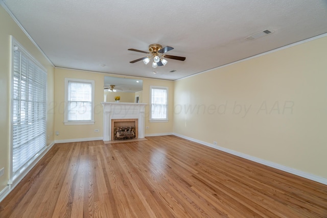 unfurnished living room with ornamental molding, a healthy amount of sunlight, light hardwood / wood-style flooring, and a textured ceiling