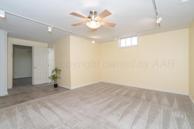 unfurnished room featuring rail lighting, a textured ceiling, and carpet