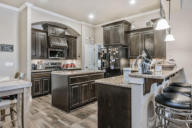 7402 Southbend Dr, Amarillo, TX 79119 - kitchen featuring stainless steel appliances, a breakfast bar area, backsplash, wood finished floors, and crown molding